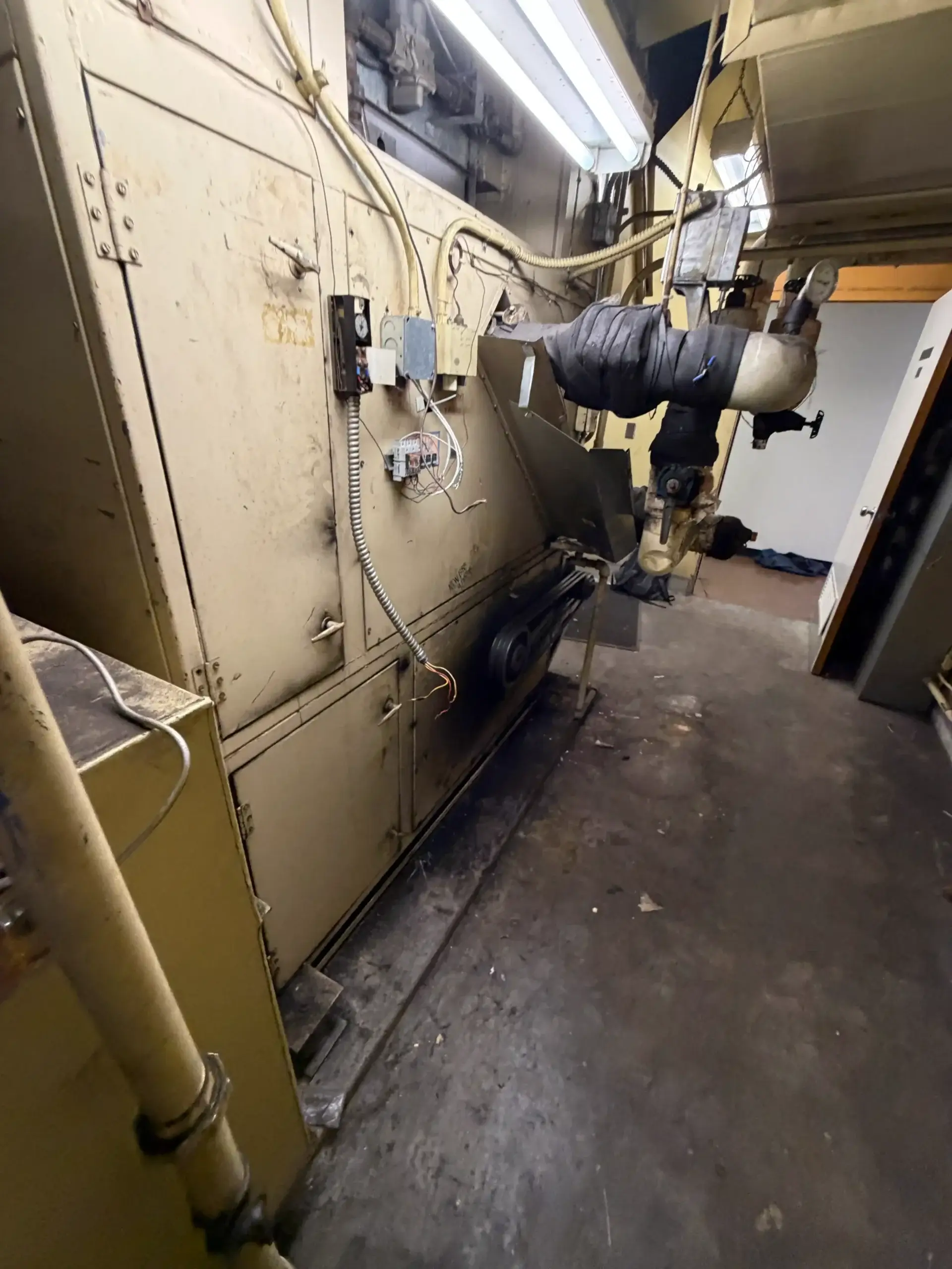 HVAC unit with ductwork and exposed wiring in mechanical room
